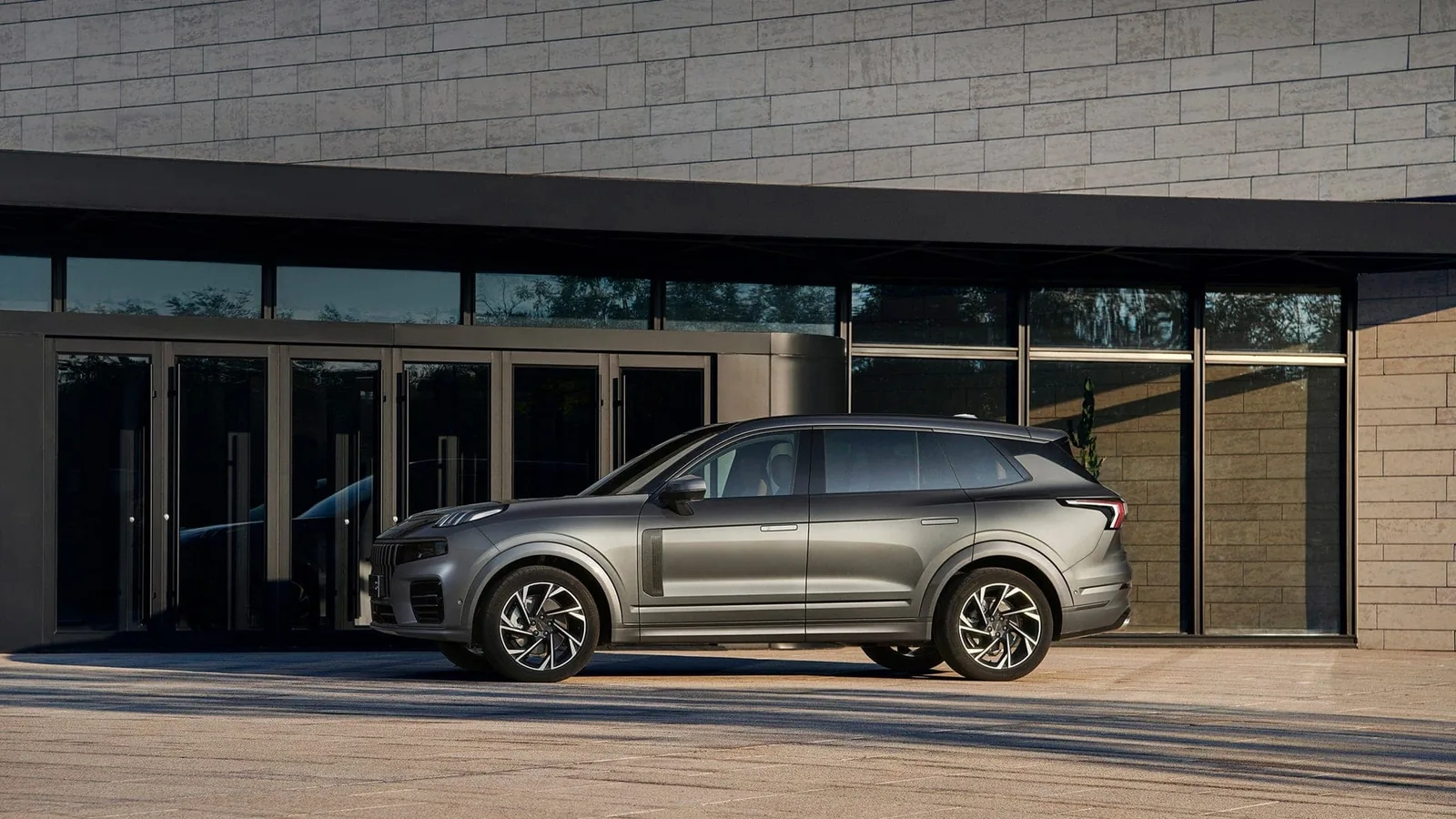 Lynk & Co 09 gris frente a un edificio moderno